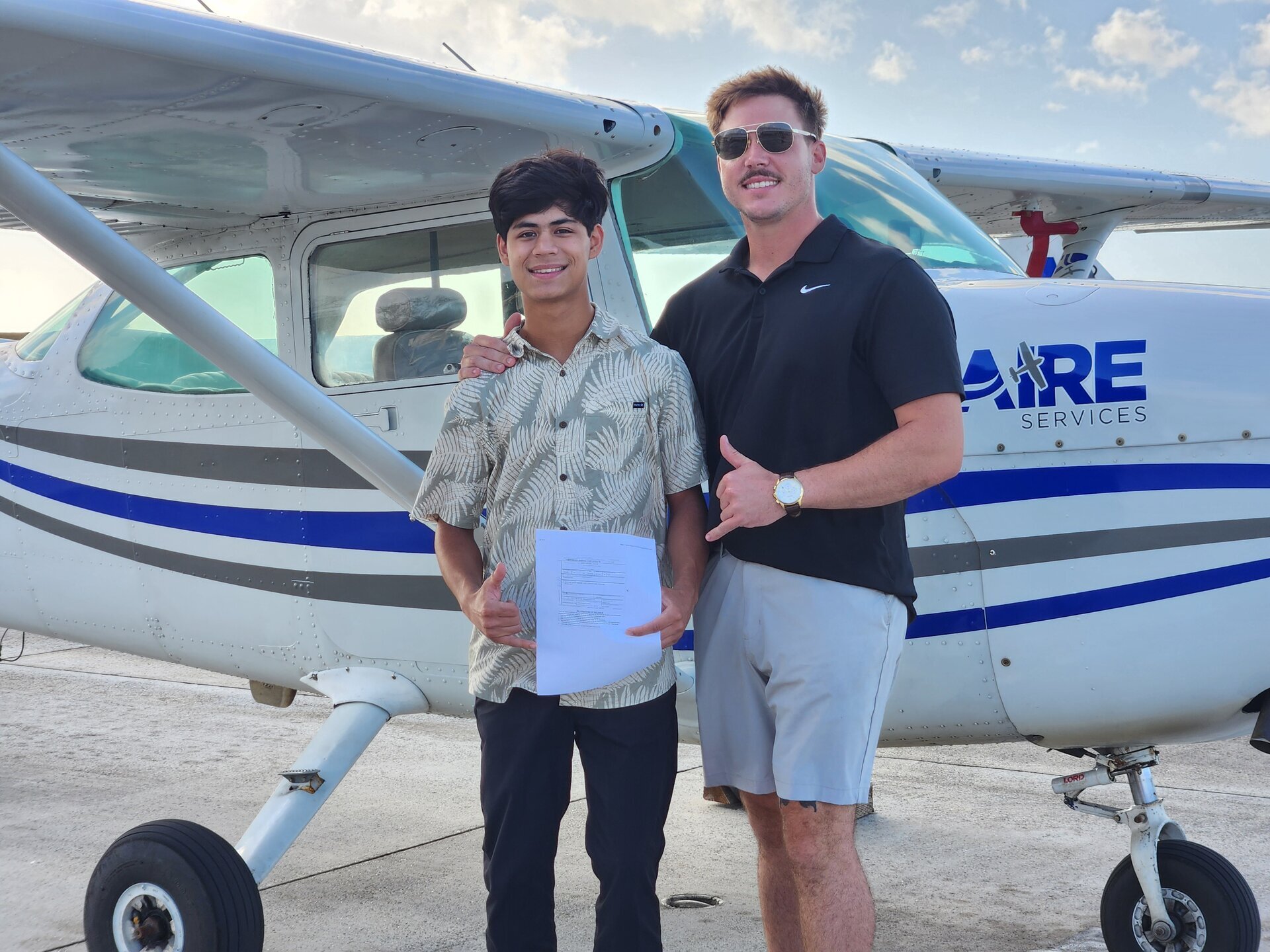 Jaden and instructor holding solo certificate in front of Cessna