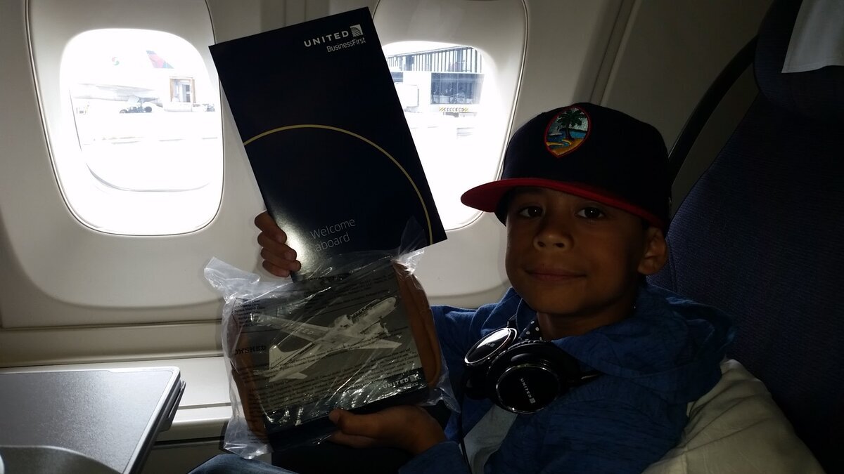 Young Jaden in Business First cabin holding welcome aboard menu