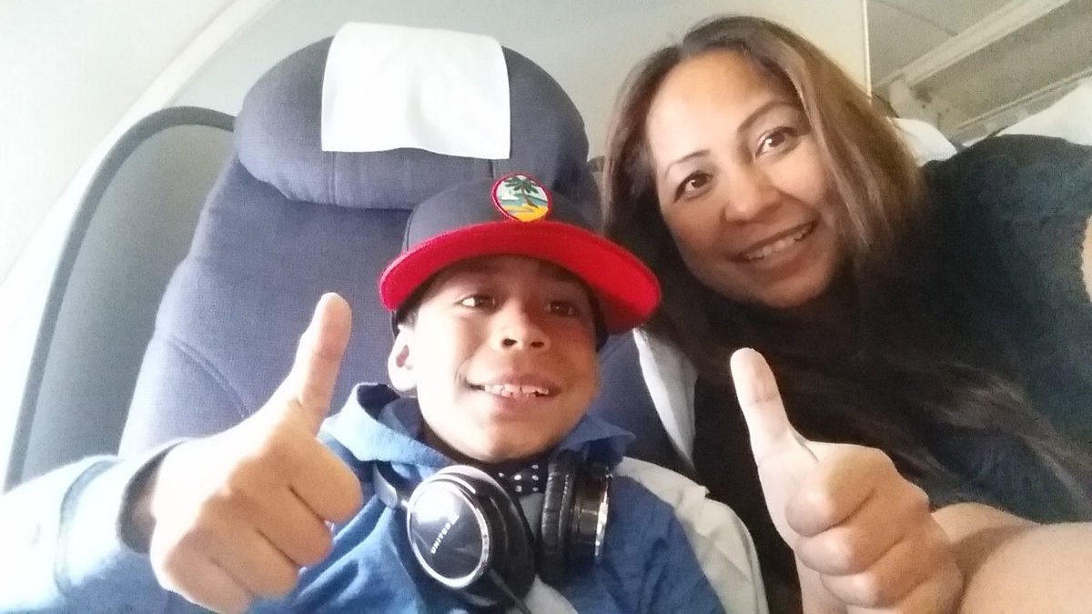 Jaden and mom on airplane giving thumbs up