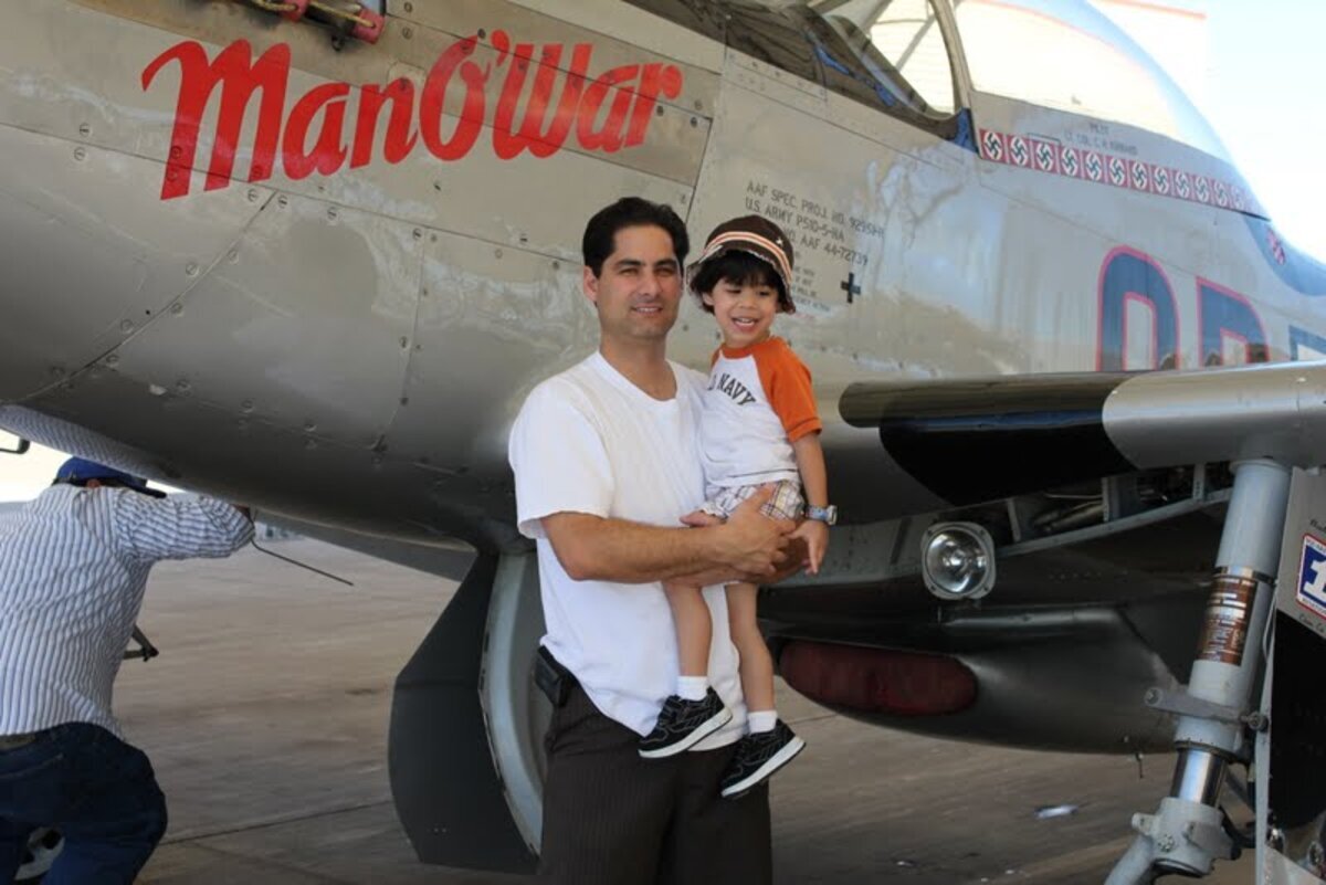 Dad holding young Jaden in front of WWII warbird Man O War